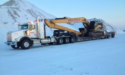 truck pulling excavator through snow